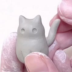 a hand holding a small white cat figurine in it's left palm