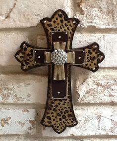 a leopard print cross hanging on a brick wall