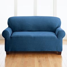 a blue couch sitting on top of a hard wood floor next to a white wall