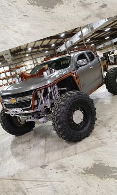 a silver truck parked inside of a garage next to other trucks in the back ground