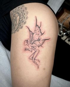 a woman's thigh with a tattoo on it that has a fairy holding a flower