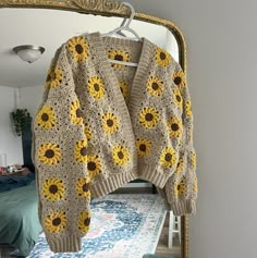 a sunflower sweater hanging on a mirror