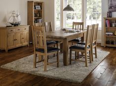 a dining room table with chairs and bookshelf in the background, next to a large window