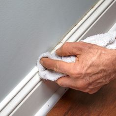 a person wiping off the edge of a window sill