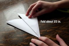 someone is folding an origami airplane on the table