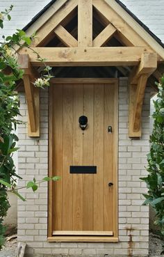 a wooden door with an arch above it in front of a white brick wall and green plants