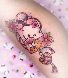 a hello kitty tattoo on the leg with flowers and an umbrella in it's corner