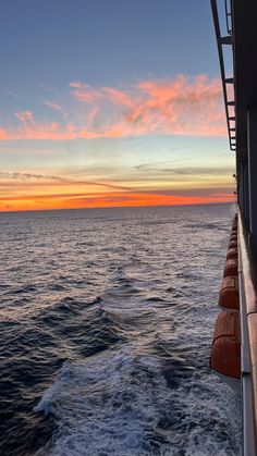 the sun is setting over the ocean as seen from a boat