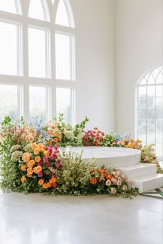 a bunch of flowers that are sitting on some steps in front of a big window