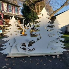 a white christmas tree with snowflakes on it in front of a house and trees