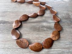 One long strand of dark brown wood beads with brown glass spacer beads.  - Length is 38"  (can vary depending on the beads)  - Beads measure 1.5" by 1" - Lead free pewter toggle (gold toggle and stainless steel clasp also available)  The necklace length can be customized. The mannequin's neck size is 14.5".  If you would like a multi strand version or other colors: www.etsy.com/shop/DanaLeBlancDesigns?ref=seller-platform-mcnav&search_query=miranda+wood  We use the highest quality findings to ens Adjustable Single Strand Brown Beads, Artisan Brown Spacer Beads, Earthy Polished Brown Beads, Earthy Brown Polished Beads, Adjustable Brown Beaded Necklaces With Oval Beads, Adjustable Brown Oval Beads, Artisan Brown Beaded Necklaces With Oval Beads, Brown Wooden Beads For Jewelry Making, Artisan Brown Beaded Necklace With Oval Beads