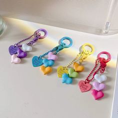 several heart shaped key chains are on a white surface next to a glass vase with water in it