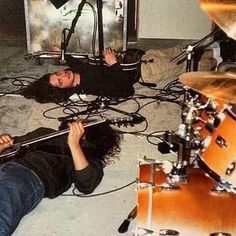 two people are laying on the floor with guitars and drums in front of their heads