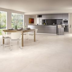 a large open kitchen and dining room area with white tile flooring on the walls