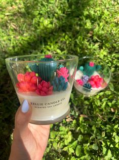 two small glass bowls filled with flowers on top of green grass and bushes in the background