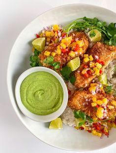 a white plate topped with rice and meat next to a bowl of guacamole