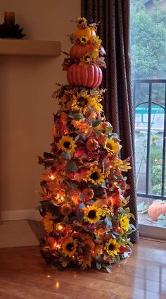 a decorated christmas tree with sunflowers and pumpkins on it in front of a window