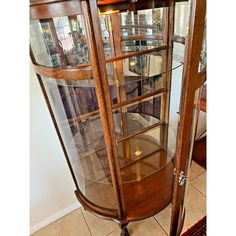 a wooden display case with glass doors on the top and bottom shelves, in front of a tiled floor