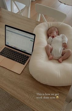 a baby is laying in a bean bag chair next to a laptop on a table