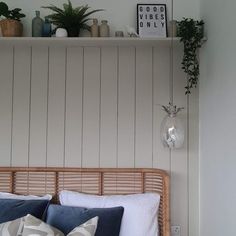 a bed with pillows and plants on top of it next to a wall mounted shelf