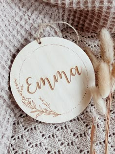 a wooden sign with the word emna on it next to some dried flowers and twigs