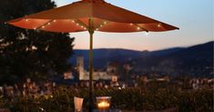 an umbrella is lit up on top of a table with two glasses and a candle