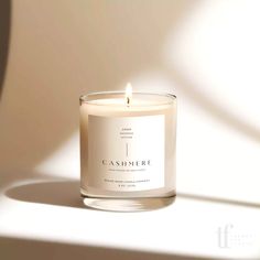 a candle that is sitting on a table next to a white wall with the words cashmere written on it