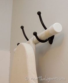 a white curtain with black handles hanging from it's side on the wall next to a toilet paper roll