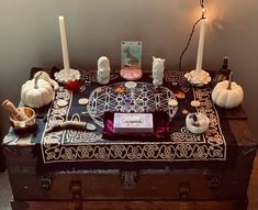 an old trunk with candles and other items on it sitting in front of a wall