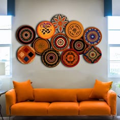 an orange couch sitting in front of a white wall with lots of plates on it