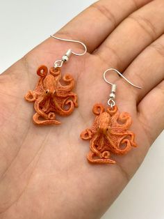 an orange octopus shaped earrings on a person's hand