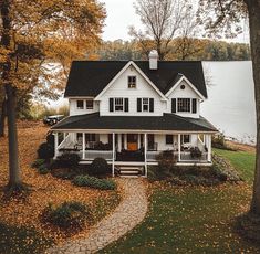 a large white house sitting on top of a lush green field next to a lake