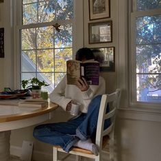 a woman sitting at a table reading a book