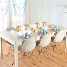 a long table with pink and blue plates on it in the middle of a room