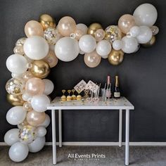 a table with champagne and balloons on it in front of a large balloon wall decoration