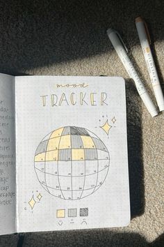 an open notebook with the words tracker written on it next to some pens and markers