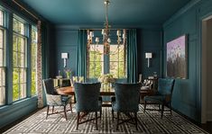 an elegant dining room with blue walls and chairs, chandelier, windows, and rug