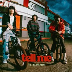 three young men sitting on their bikes in front of a building with the words tell me