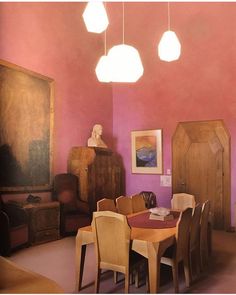 a dining room with pink walls and wooden furniture