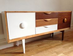 a white and brown dresser sitting on top of a hard wood floor next to a wall