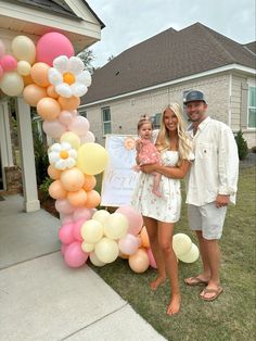 a man and two women standing in front of a house with balloons on the lawn