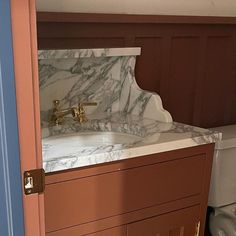 a bathroom with a sink and toilet next to a wooden cabinet in the middle of it