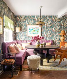 a living room with colorful wallpaper and purple couches in front of a round table