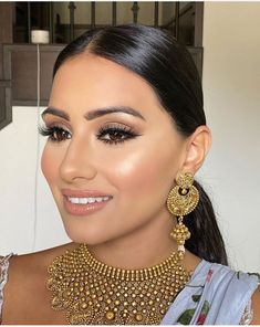 a woman wearing a gold necklace and matching earrings