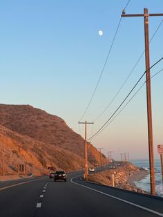 pacific coast highway on a curve around an amber mountain at sunset with moon visible in the still-blue sky just beyond the telephone wires, ocean tide coming in toward the rocky beach off to the right Pacific Highway California, California Cool Aesthetic, Highway One California, Norcal Beach Aesthetic, Rural California Aesthetic, Sonoma California Aesthetic, Y2k California Aesthetic, Great Ocean Road Aesthetic, Southern California Aesthetic Home