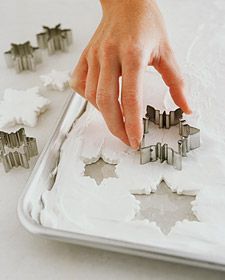 someone is placing cookie cutters on top of the icing to make snowflakes