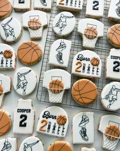 cookies decorated to look like basketballs and jerseys are arranged on a cooling rack for display