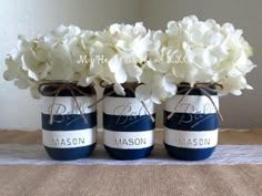 three mason jars with white flowers in them