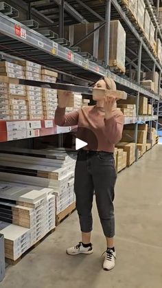 a woman is talking on her cell phone while she stands in front of stacks of boxes