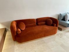 an orange couch sitting in the middle of a living room next to a blue chair